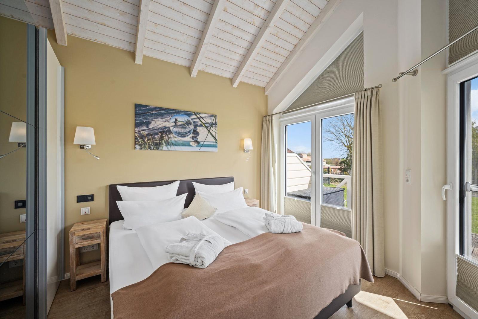 Schlafzimmer mit Doppelbett, Fenster und Holzboden.