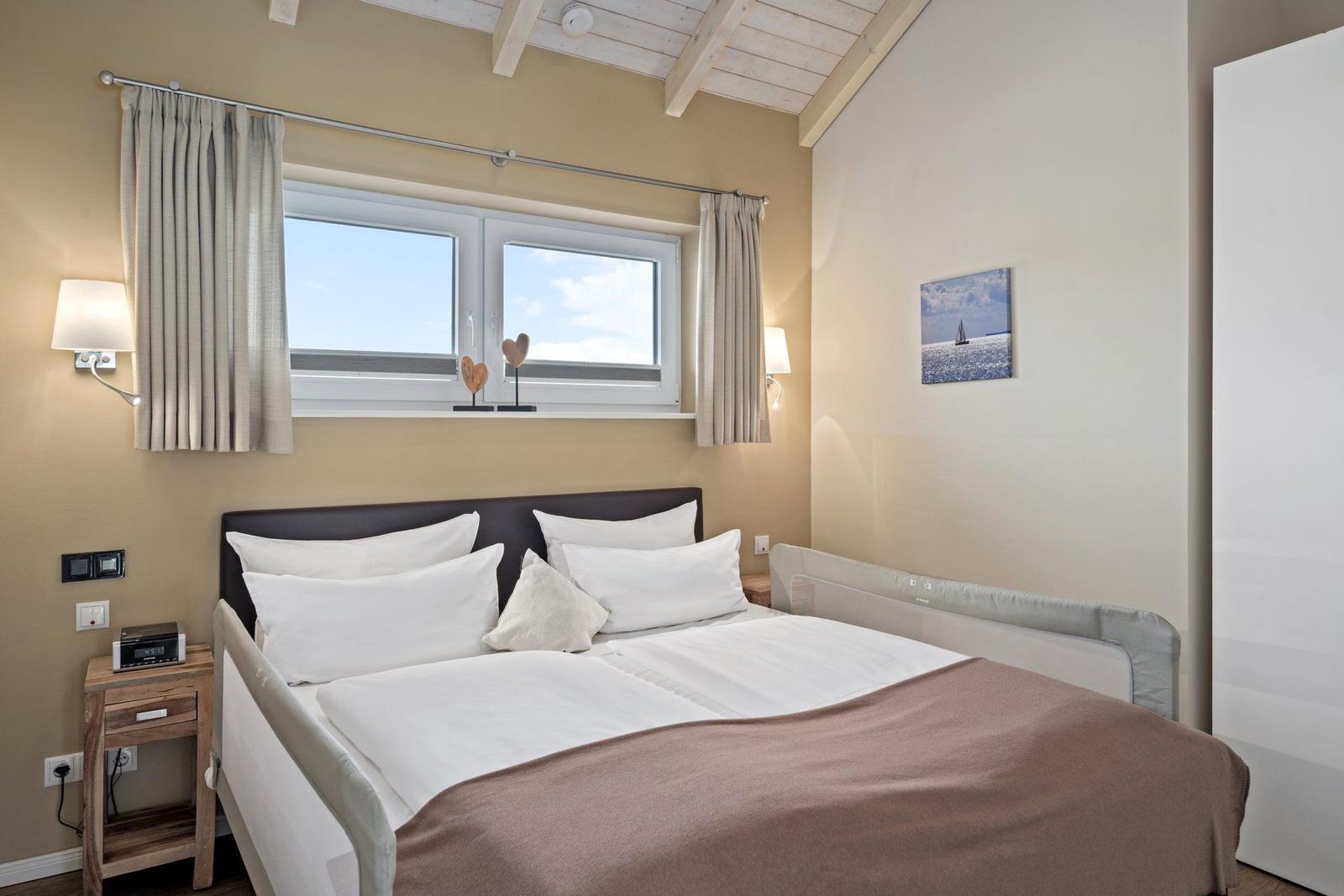Schlafzimmer mit Doppelbett, Fenster und Wandbild.