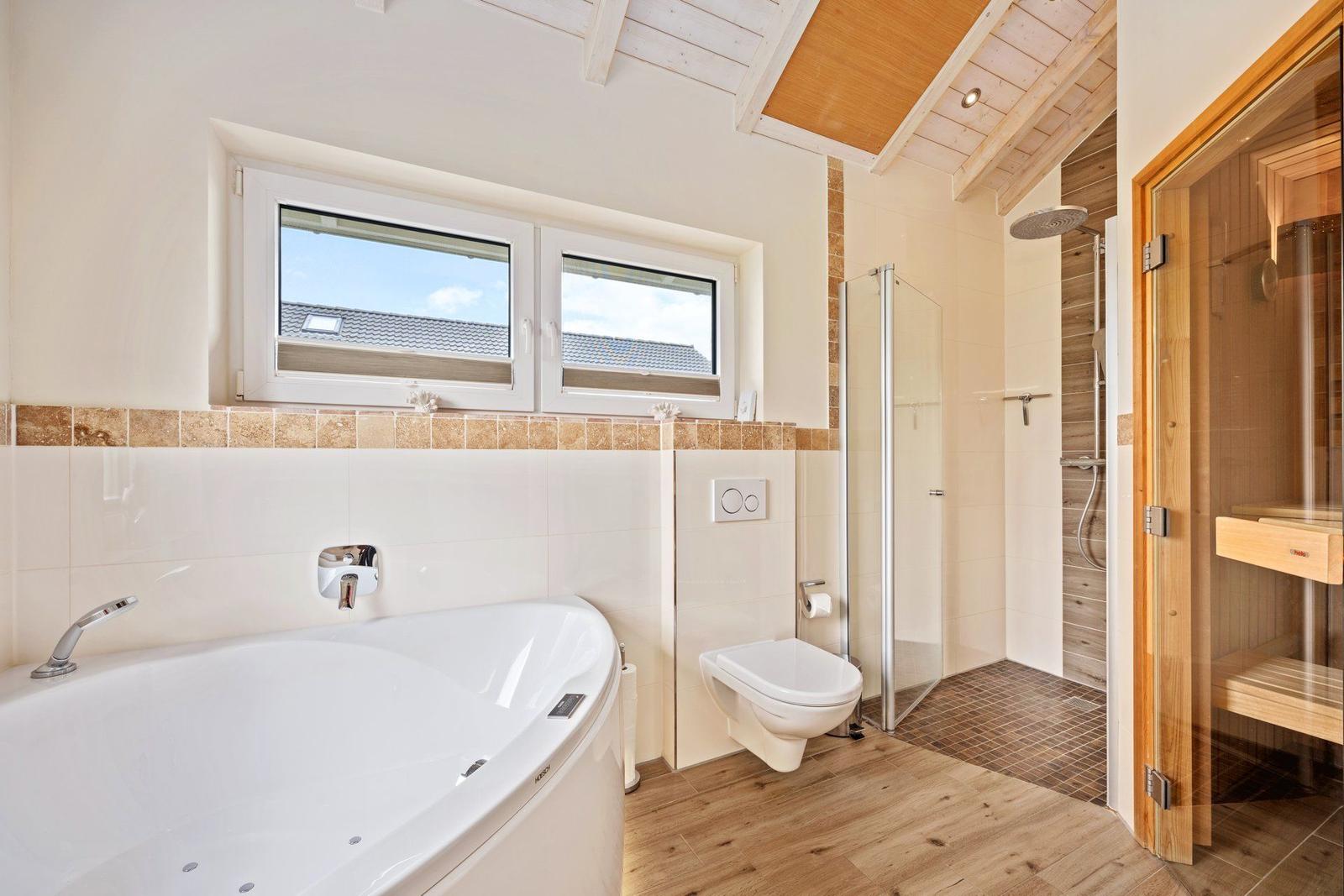 Bad mit Whirlpool, Dusche und Sauna. Holzdecke und Fenster mit Blick.