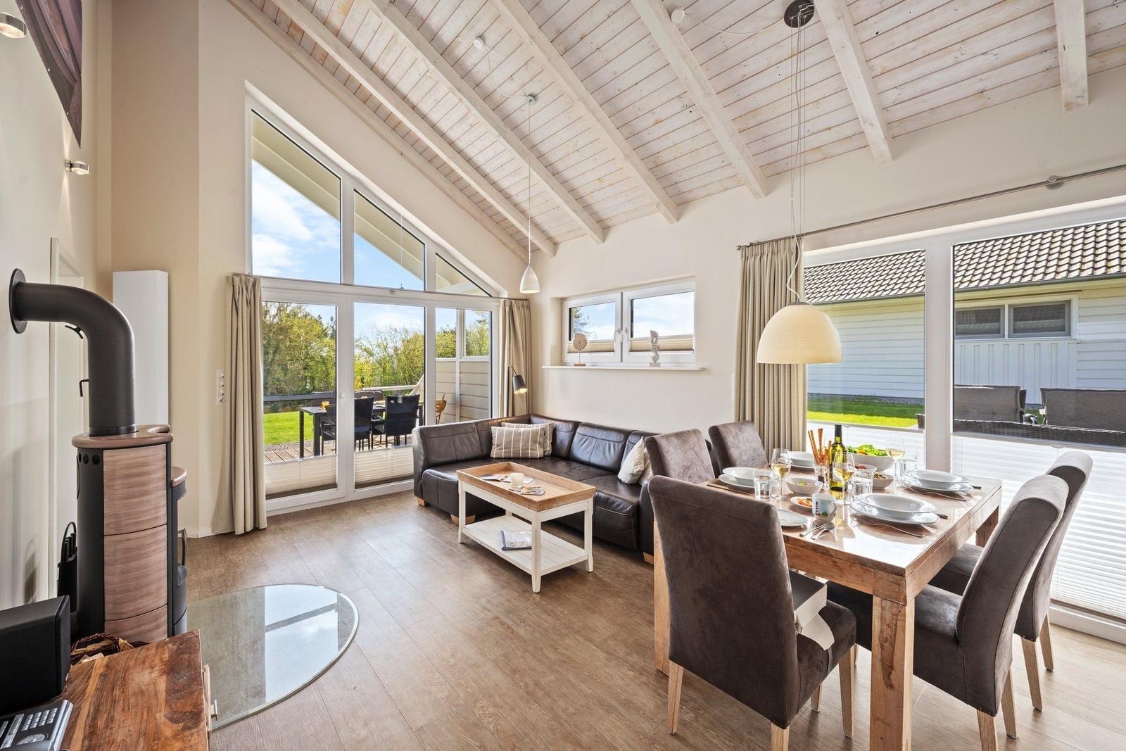 Wohn- und Essbereich mit Holzdecke, Sofa, Esstisch und Blick auf Garten