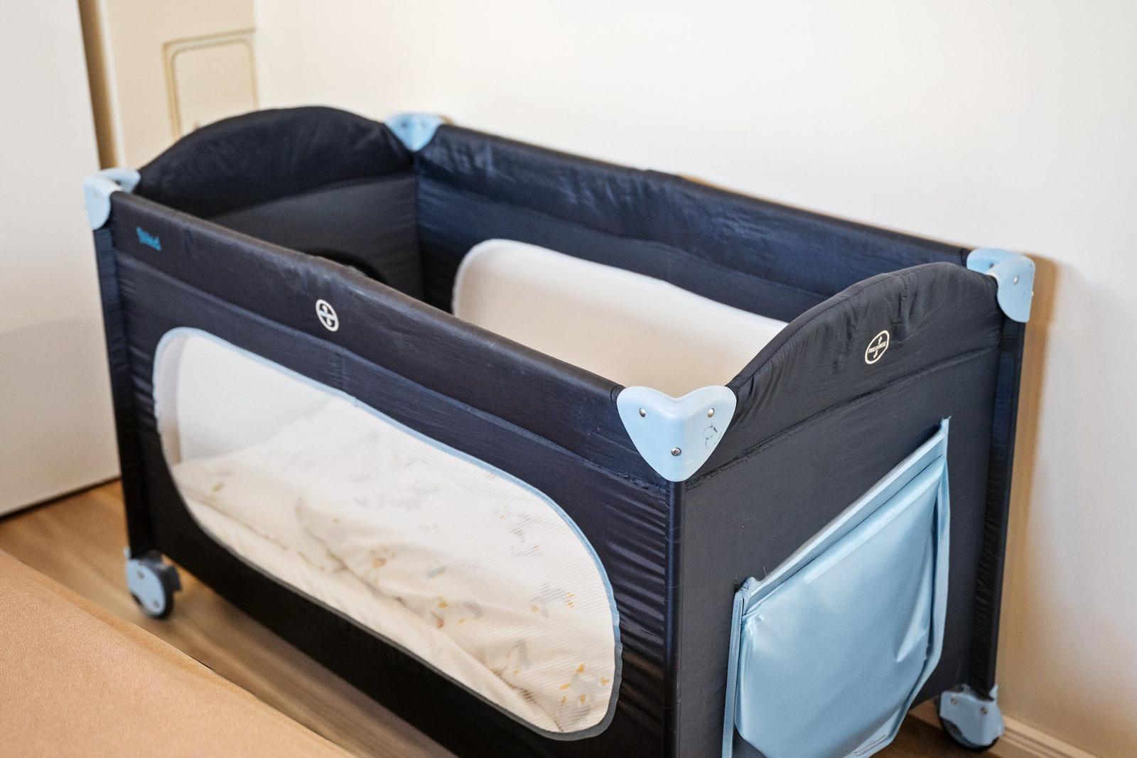 Ein tragbarer Kinderbett mit Rollen und einem Gitterfenster.