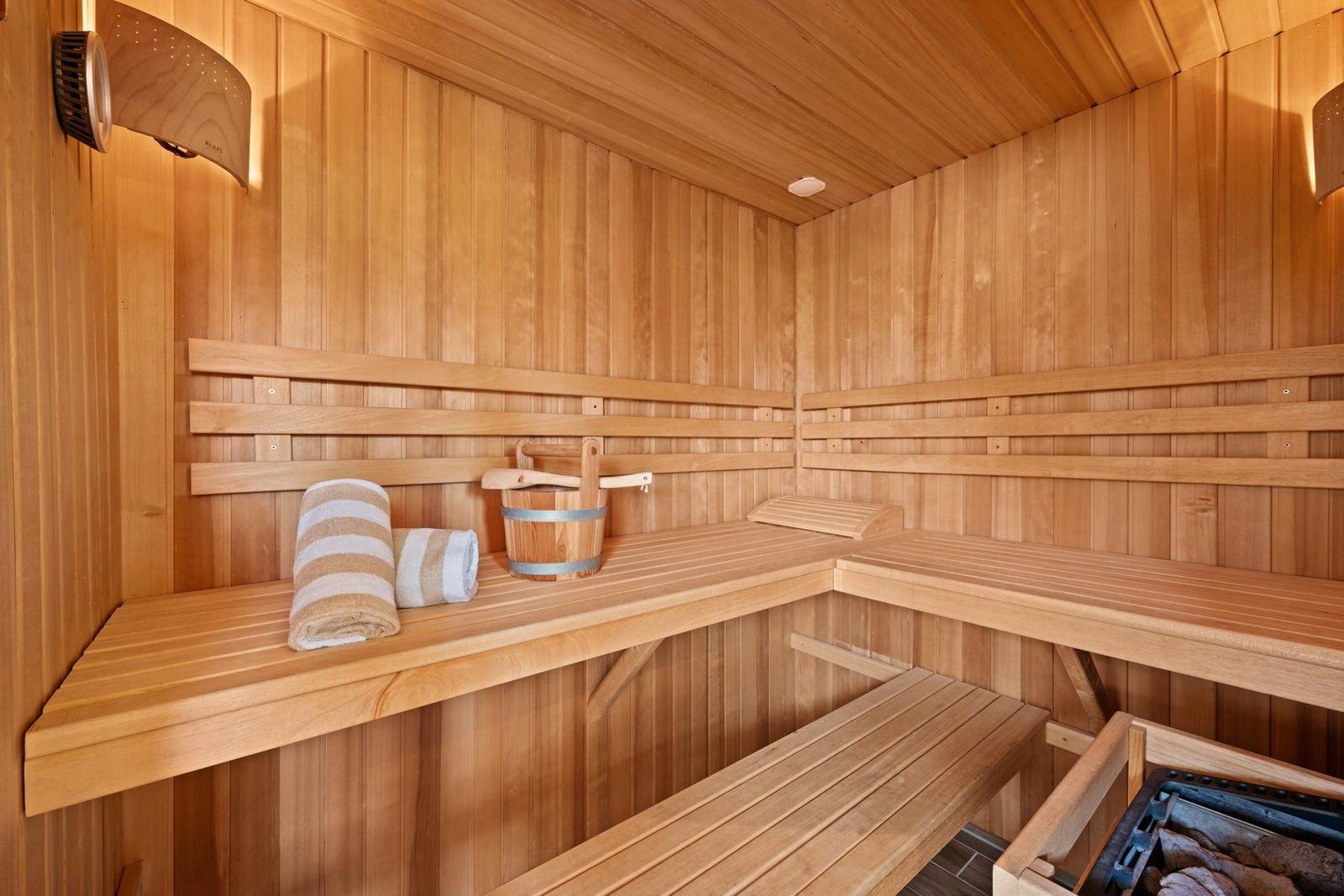 Sauna mit Holzbank, Handtuch und Eimer.