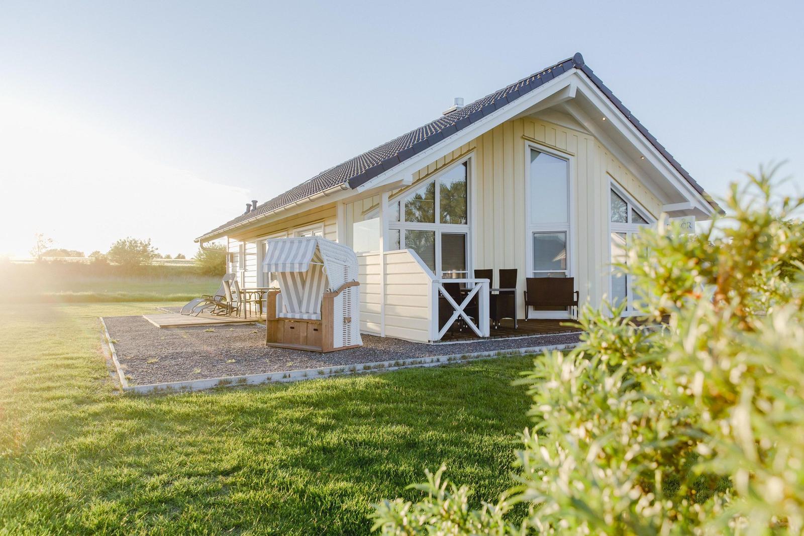 Ein Haus mit Terrasse, Strandkorb und Garten.
