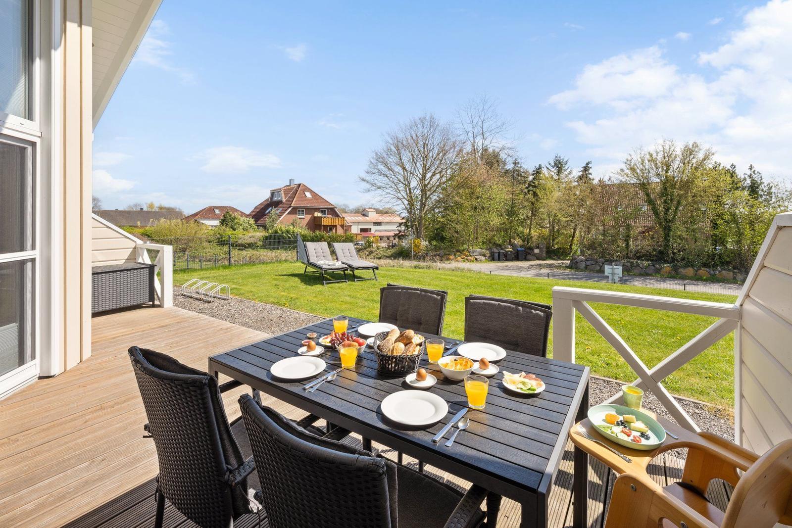 Terrasse mit Esstisch, Stühlen und Blick auf Garten und Häuser