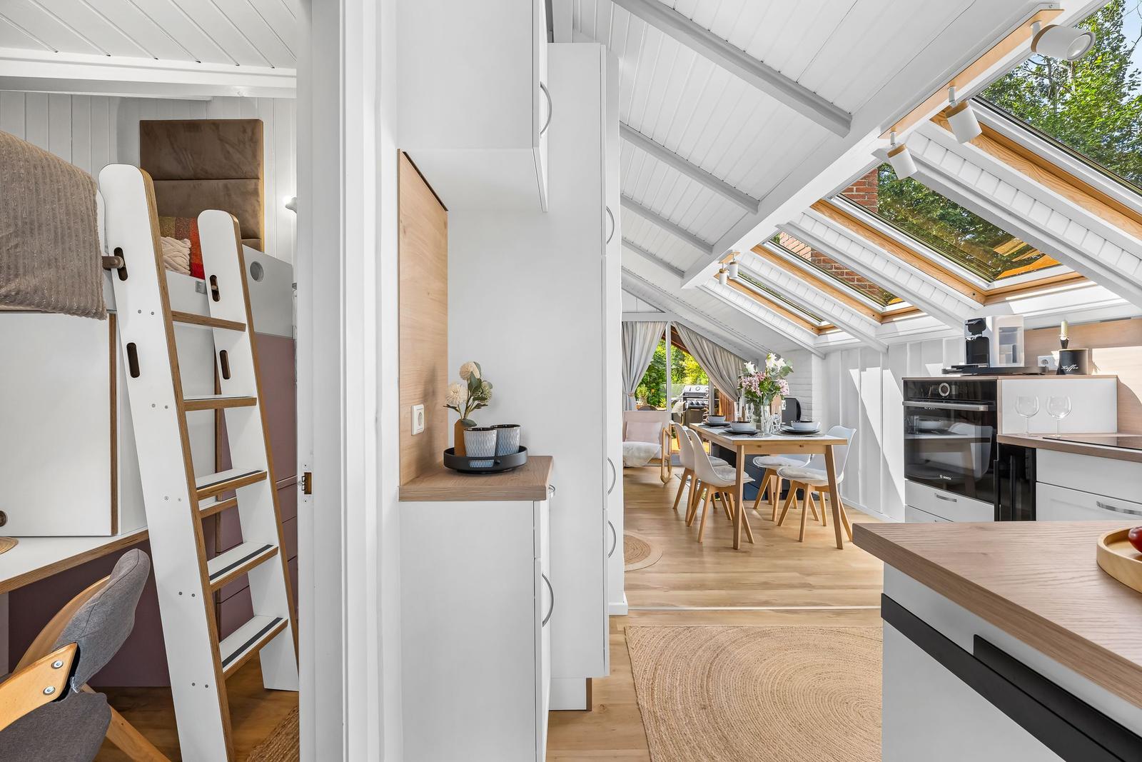 Wohnung mit Schlafgelegenheit, Essbereich und Küche unter Dachschrägen mit Dachfenstern.