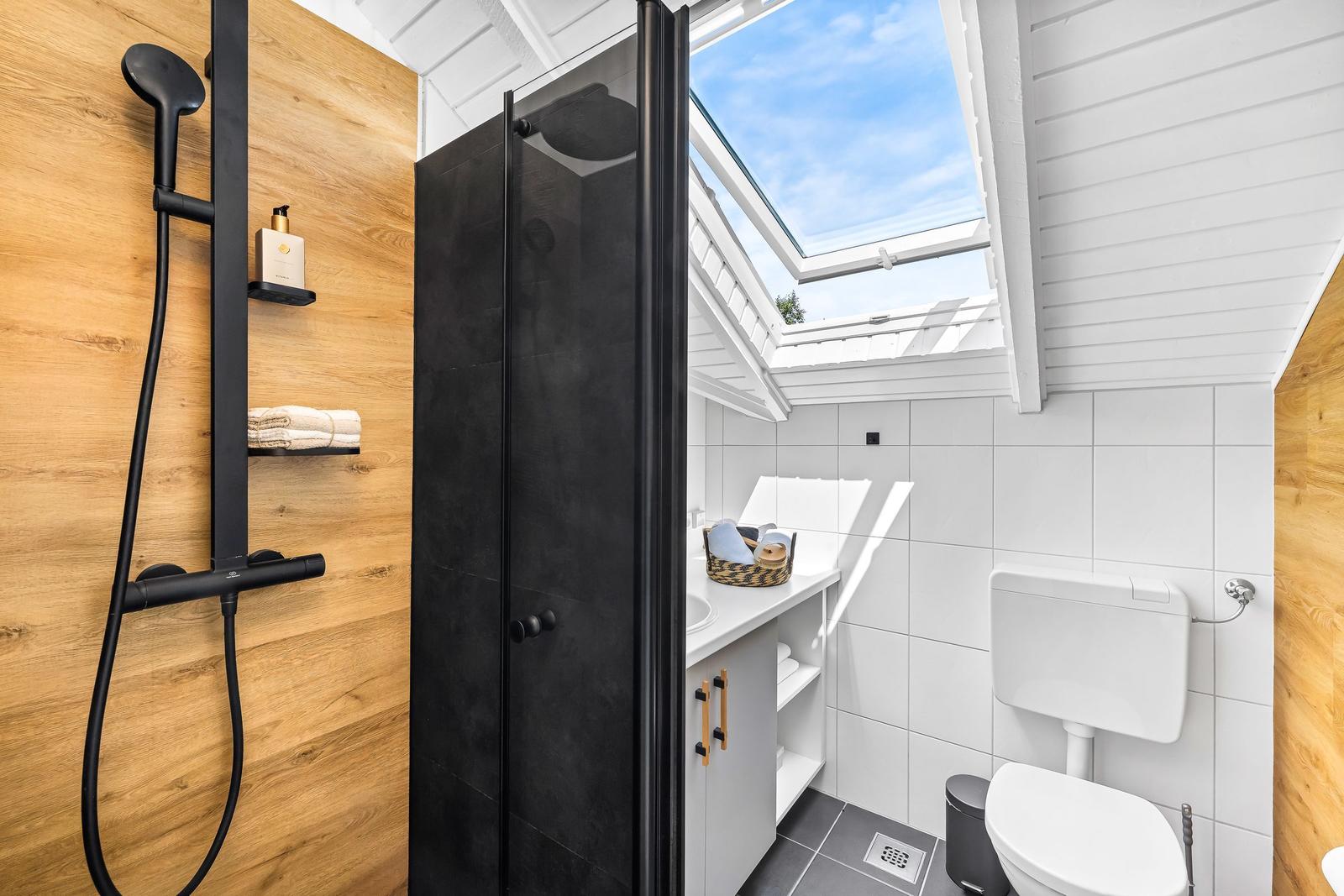 Badezimmer mit Dusche, Toilette und Waschbecken unter Dach