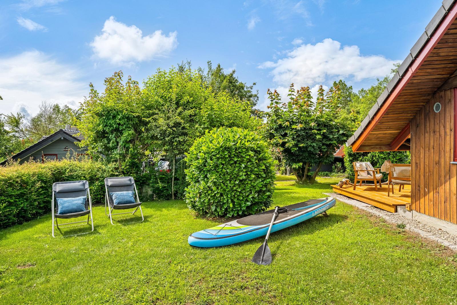 Garten mit Liegestühlen, Stand-Up-Paddle und Terrasse an Holzhaus