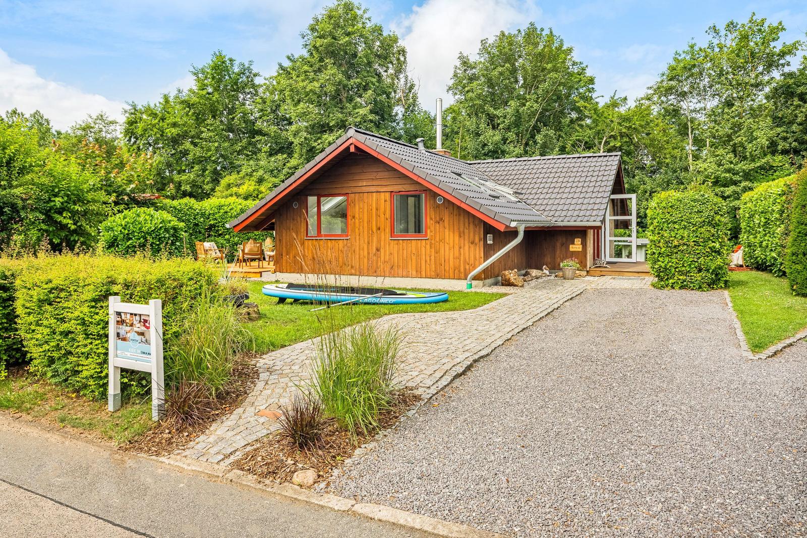 Holzhaus mit Garten, Terrasse und Stand-Up-Paddle auf dem Rasen.
