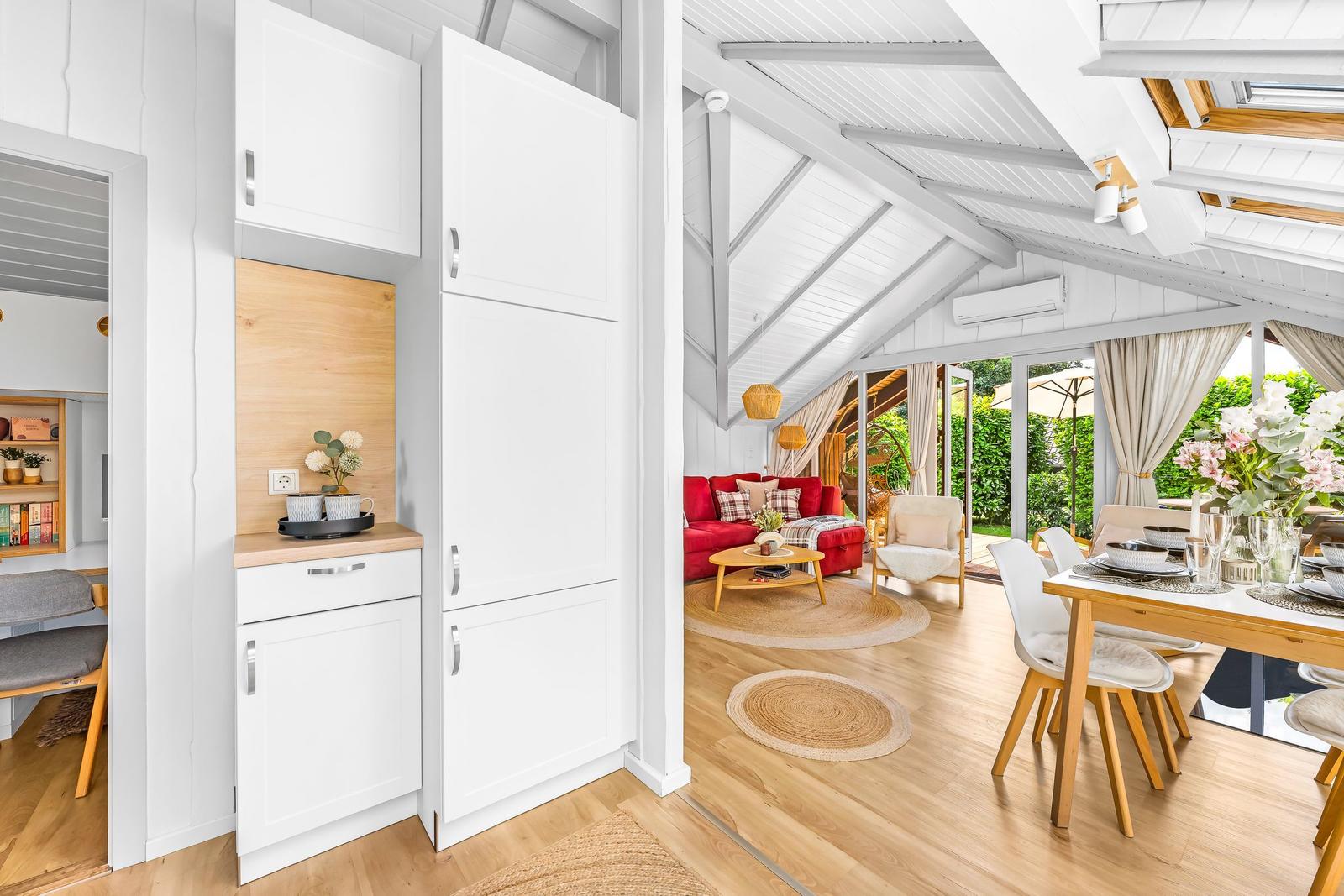 Wohnung mit Küche, Essbereich und Wohnzimmer mit rotem Sofa und Holzboden.