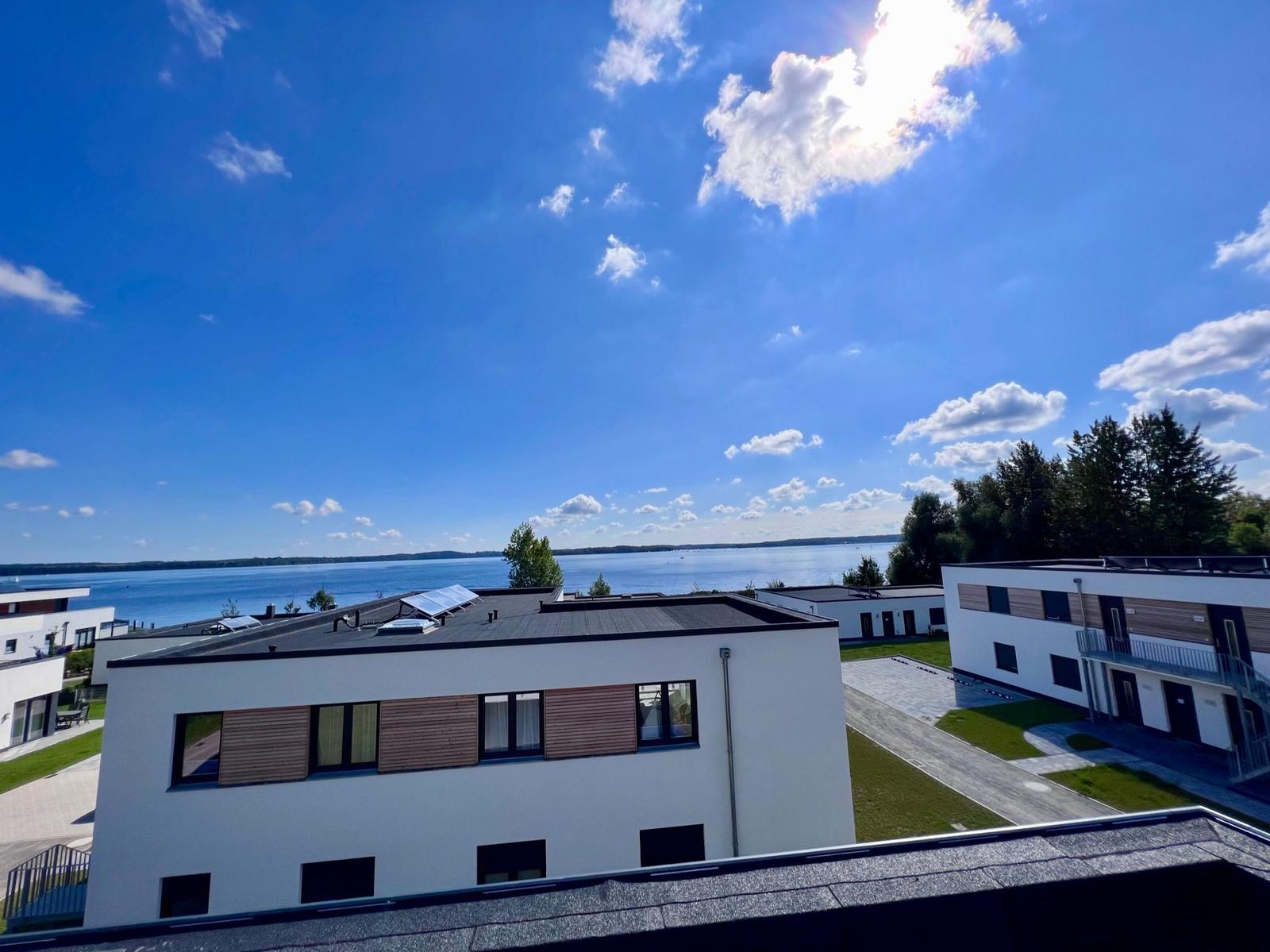 Modern building with view of calm water under blue sky with white clouds.
