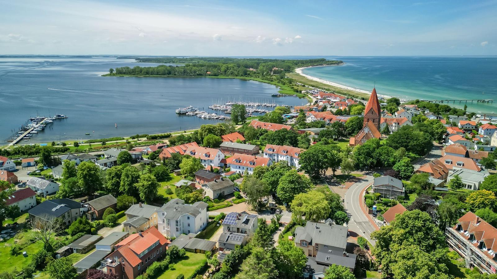 Aerial view of a coastal town with harbor, beach, and church.