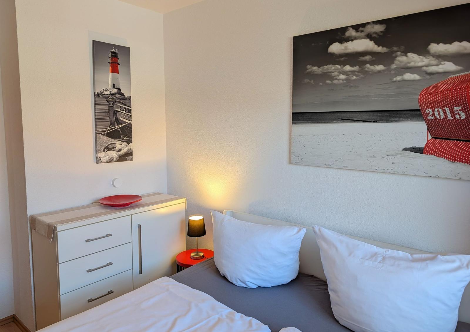 Schlafzimmer mit Bett, Nachttisch und Wandbildern