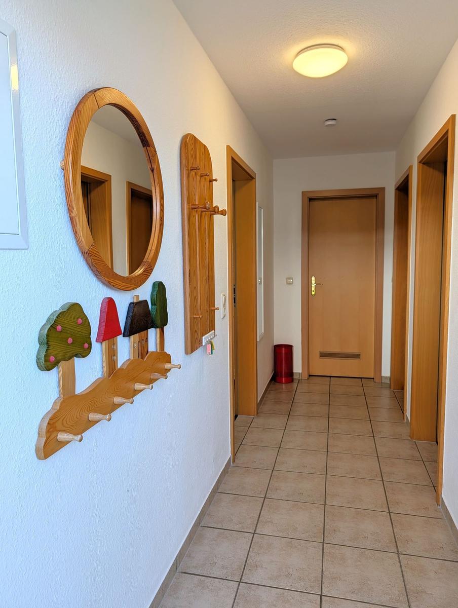 Flur mit Holzspiegel, Kleiderhaken und Tür zu Wohnraum