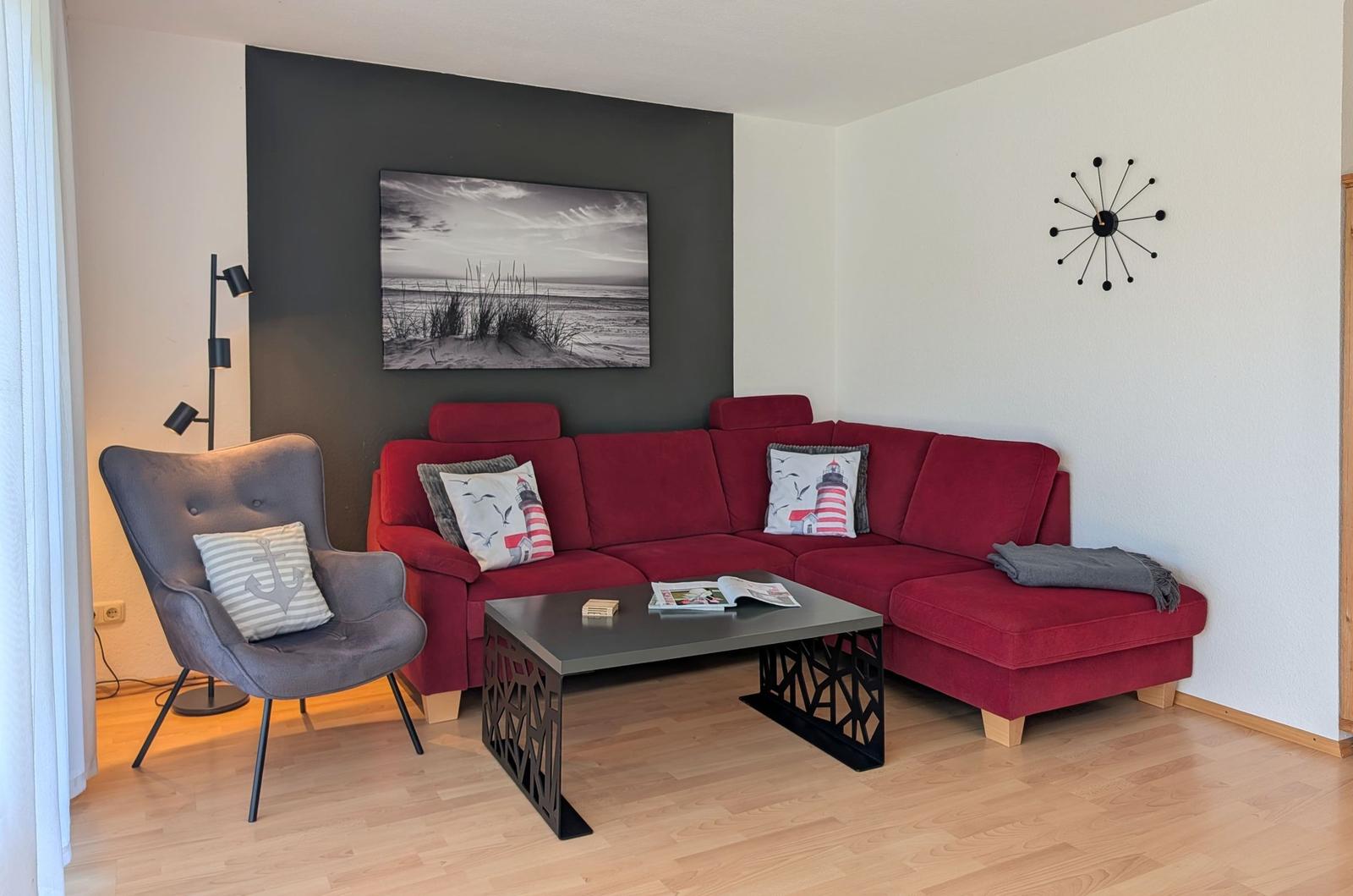 Rotes Ecksofa, graue Sessel, Tisch und Wandbild im Wohnzimmer.