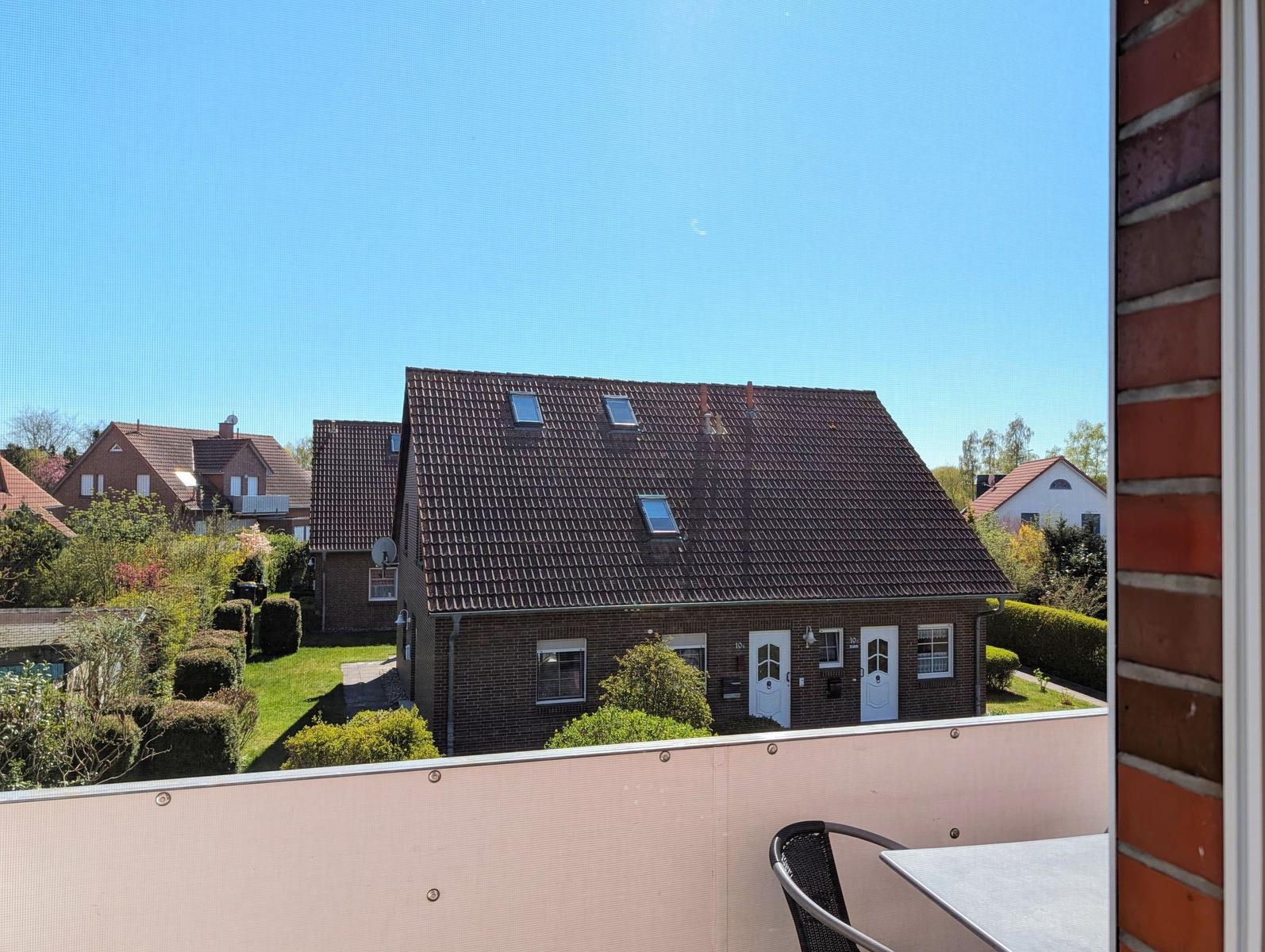 View from balcony onto a house with skylights and manicured garden.