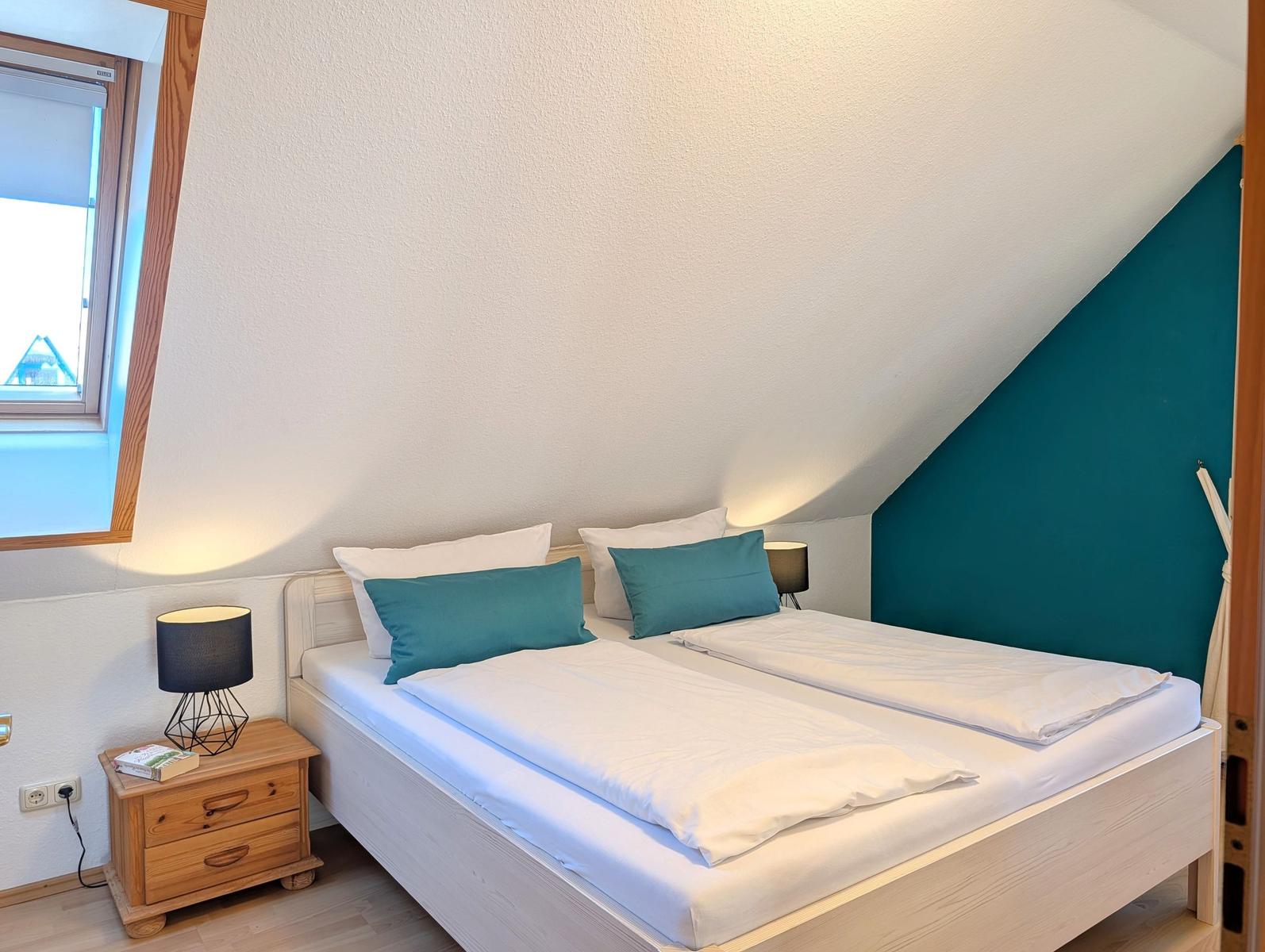 Bedroom with double bed, nightstand, and window under sloped ceiling.