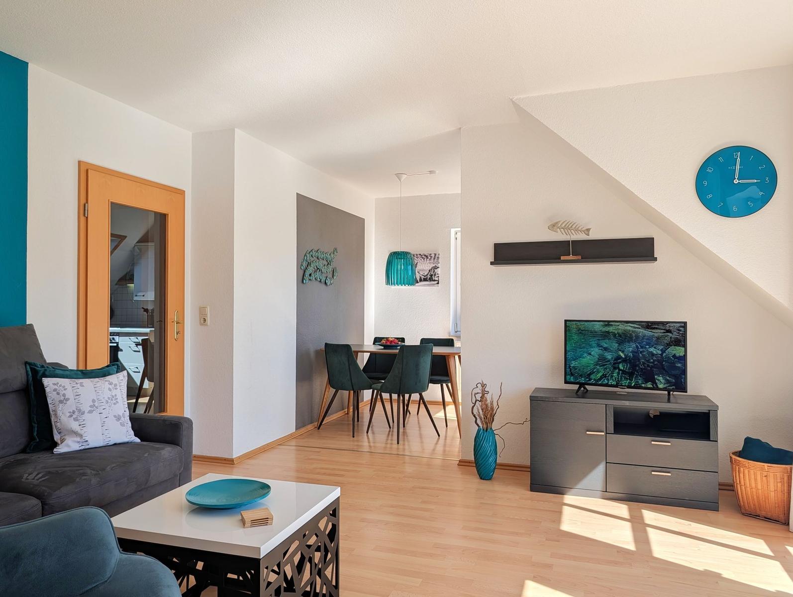 Living and dining area with TV, table, chairs, and blue decor.