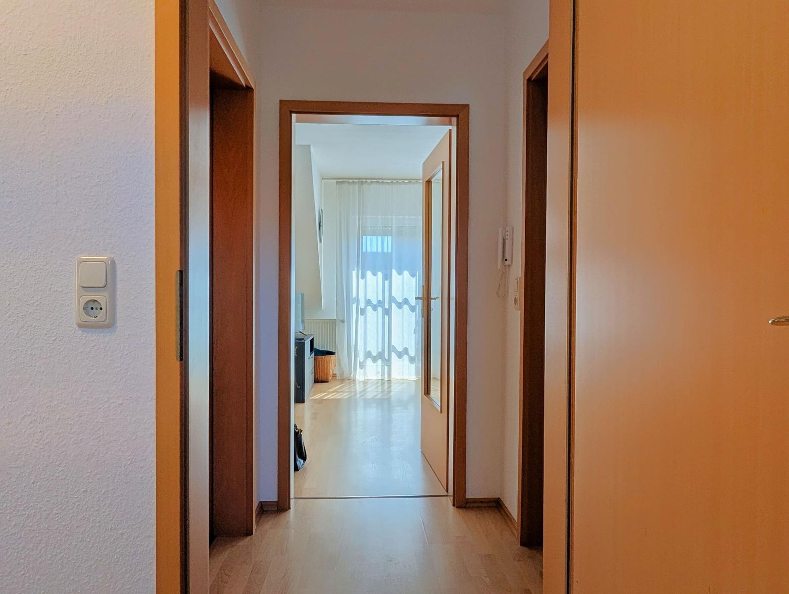 Hallway with wooden doors and light leading to the living area.