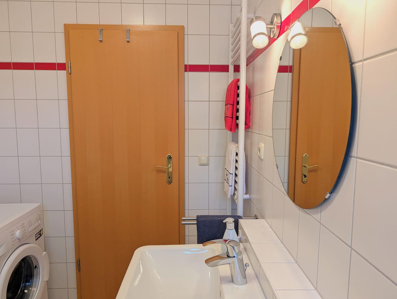 Bathroom with washing machine, mirror, and towel rack.