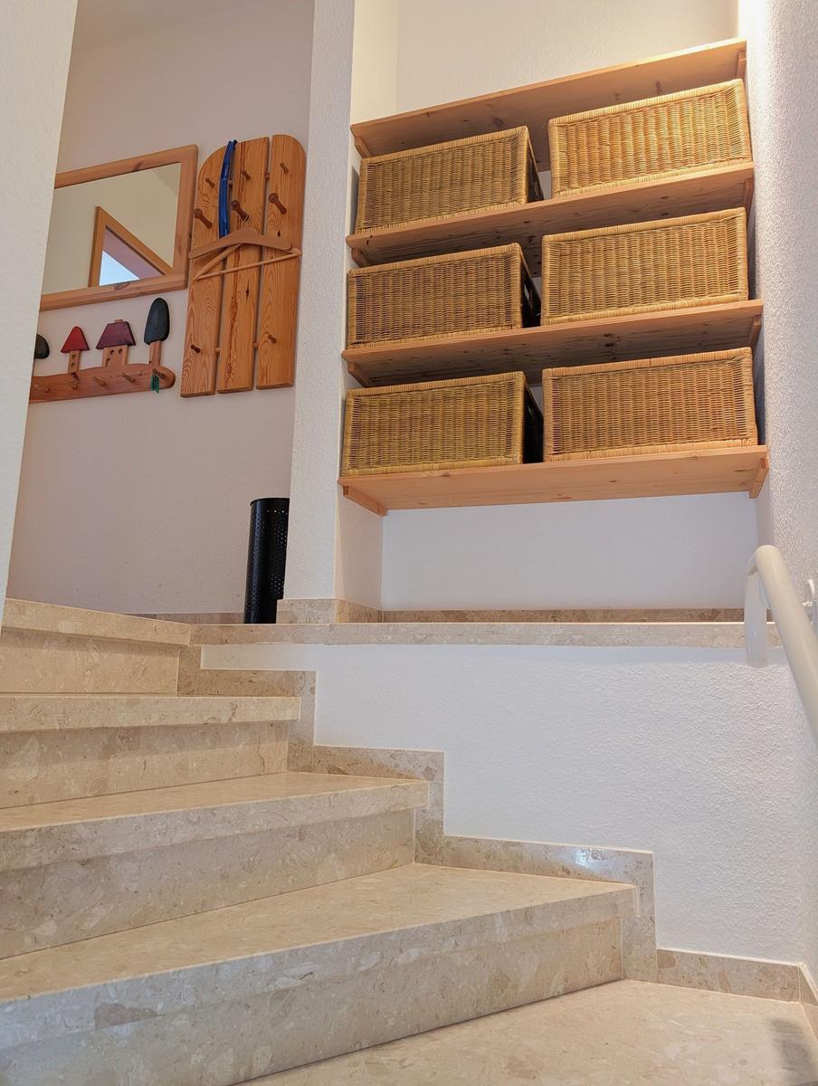 Staircase with stone steps and wooden shelves with baskets on the wall.