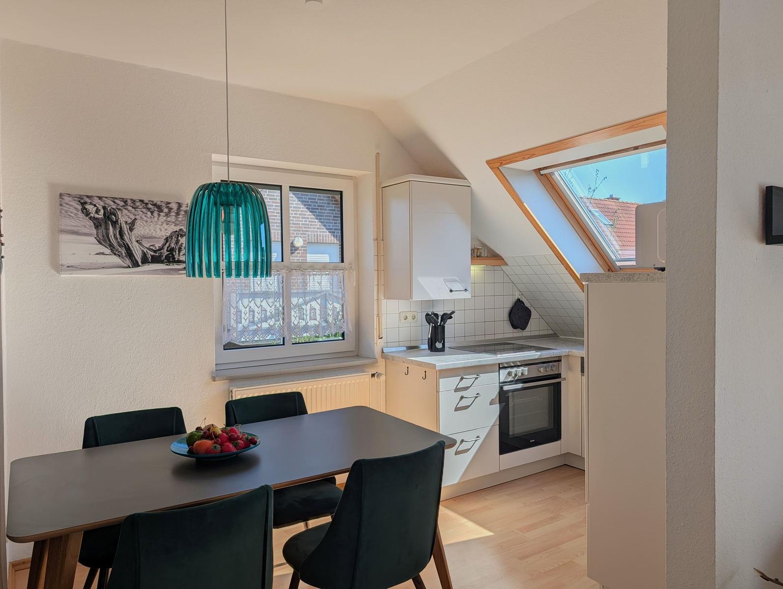 Dining area with table and chairs, kitchen with stove and skylight.
