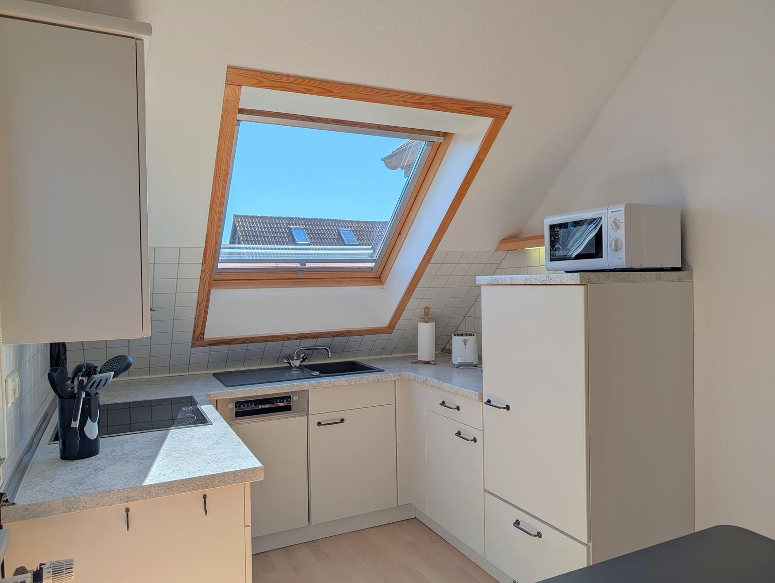 Kitchen with skylight, sink, stove, and microwave.