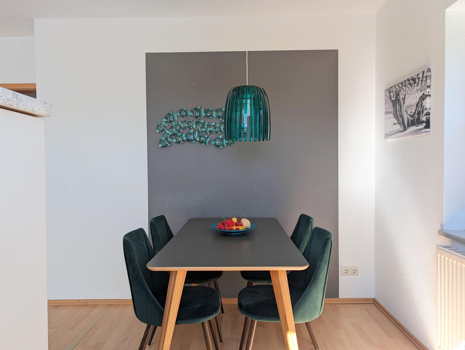 Dining area with table, chairs, and pendant light on gray wall