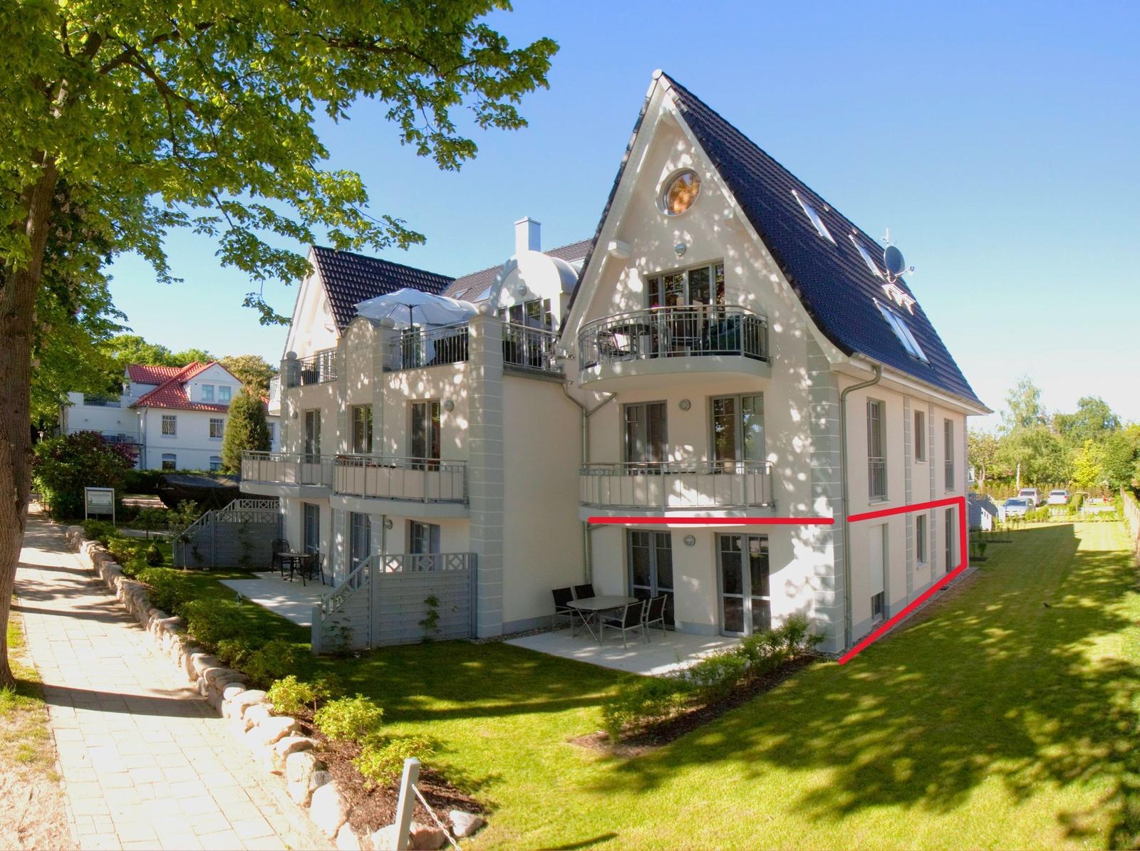 Modern multi-family house with balconies and garden area.
