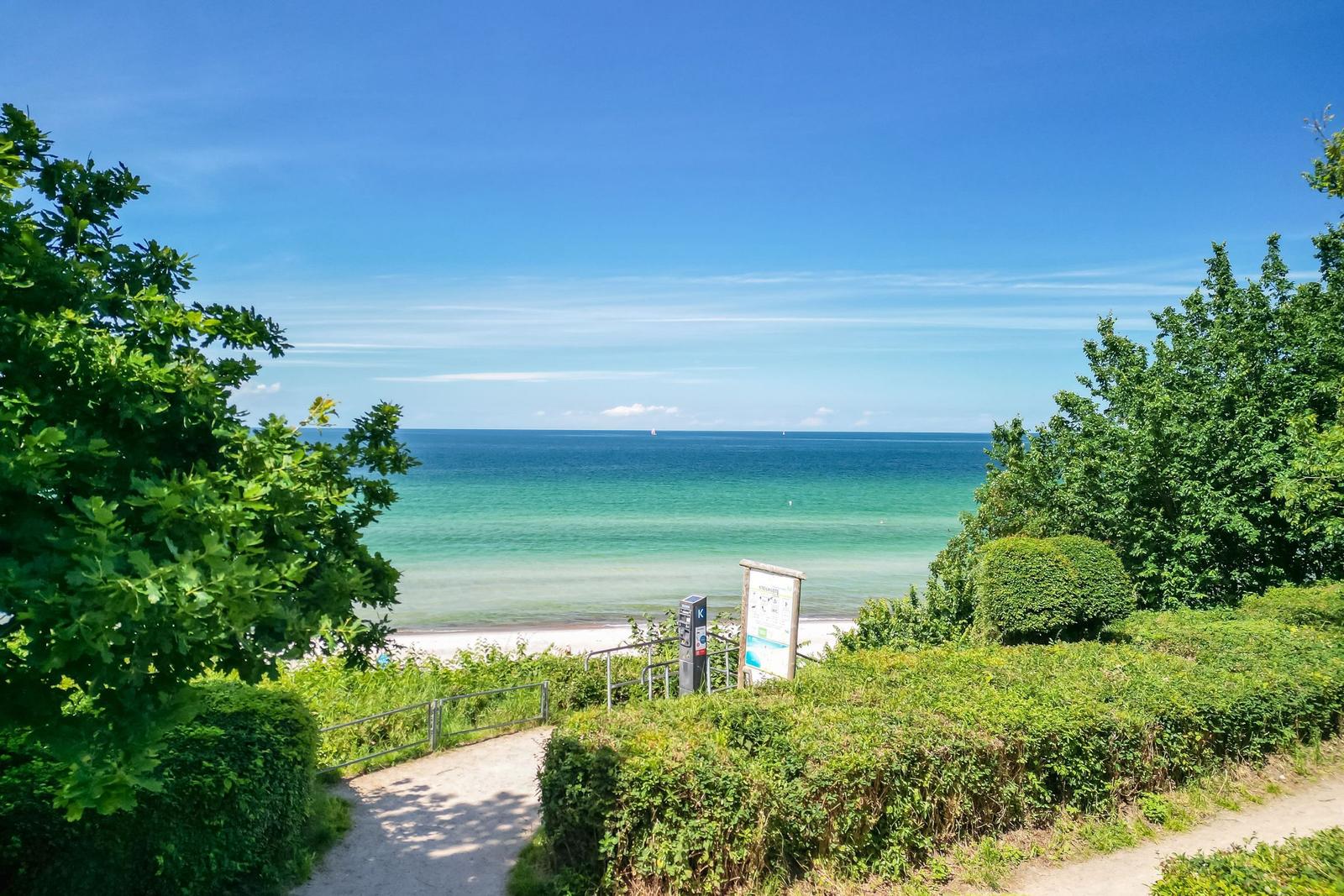 Path leads to the beach promenade with view of the sea and sky.