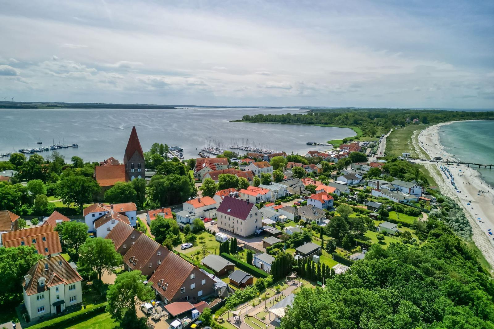 Aerial photo of a village by water with beach and boats.