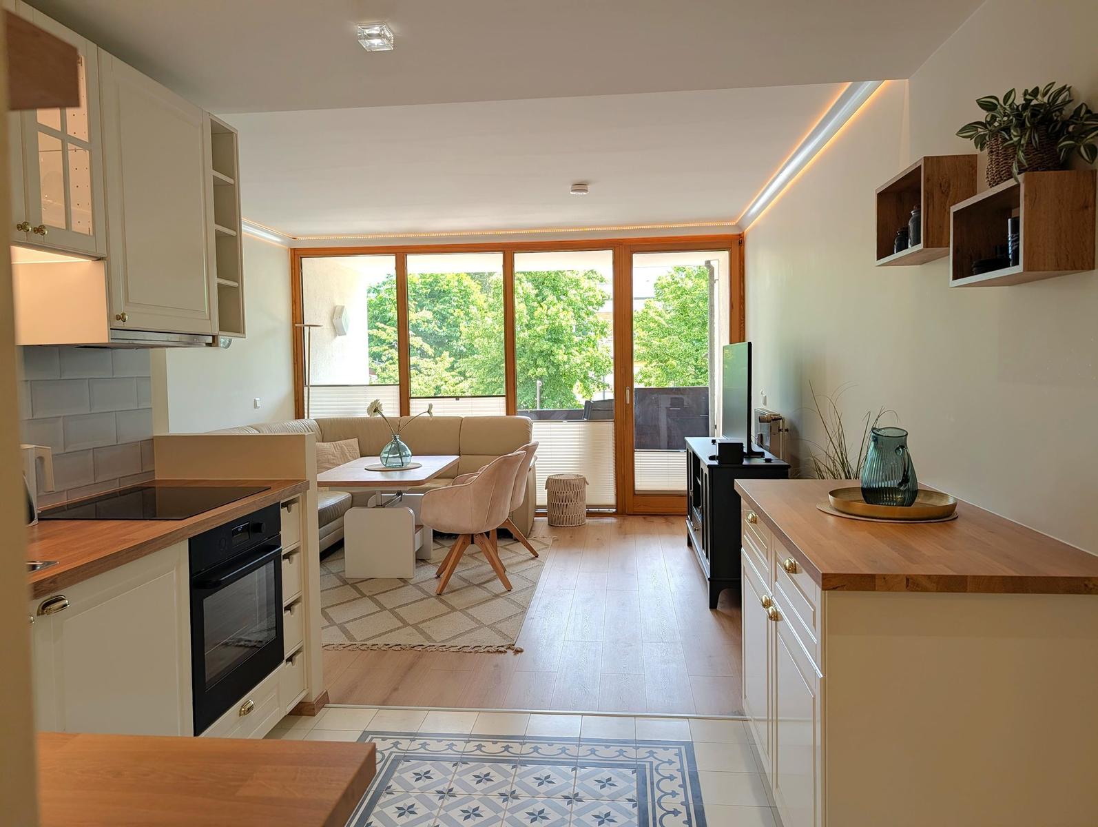 Küche mit Essbereich und Wohnzimmer mit Balkon und Holzboden.