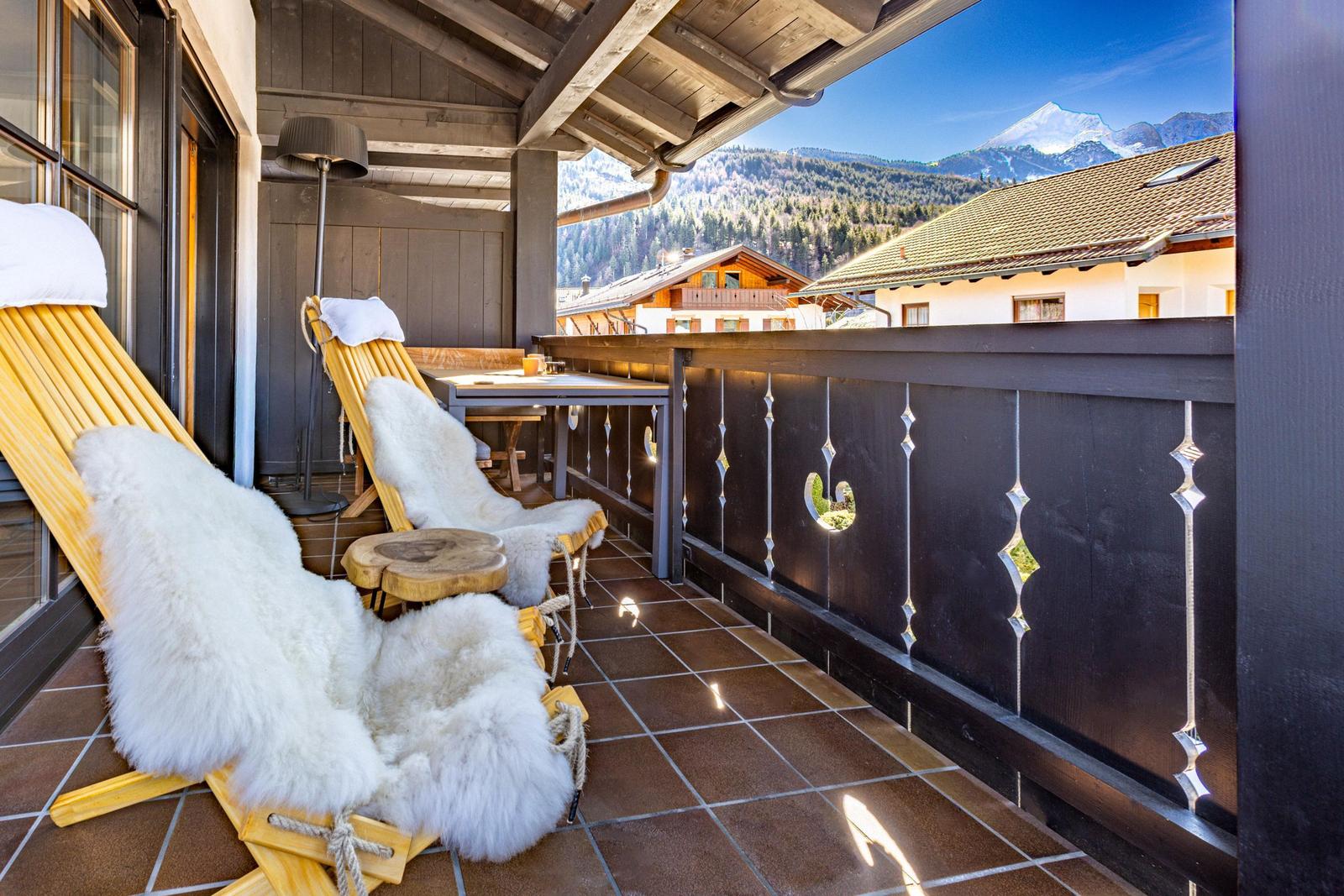 Terrasse mit zwei Liegestühlen, Felldecken und Bergblick.