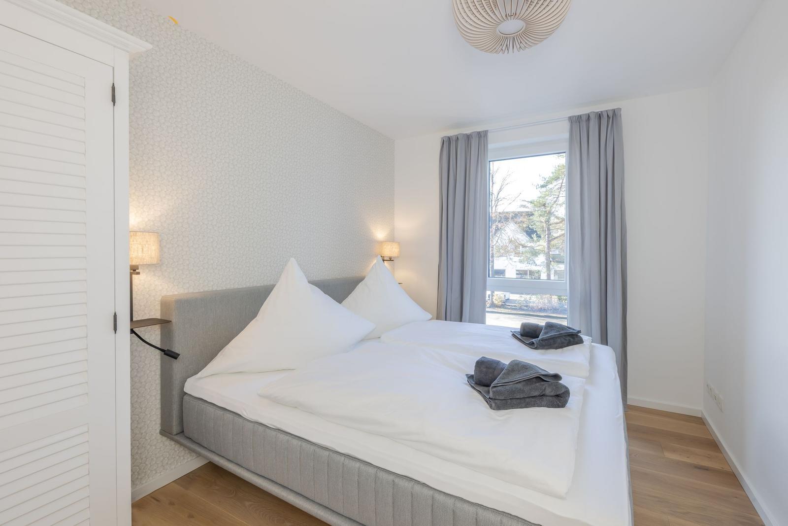 Schlafzimmer mit Doppelbett, Fenster und Holzboden.
