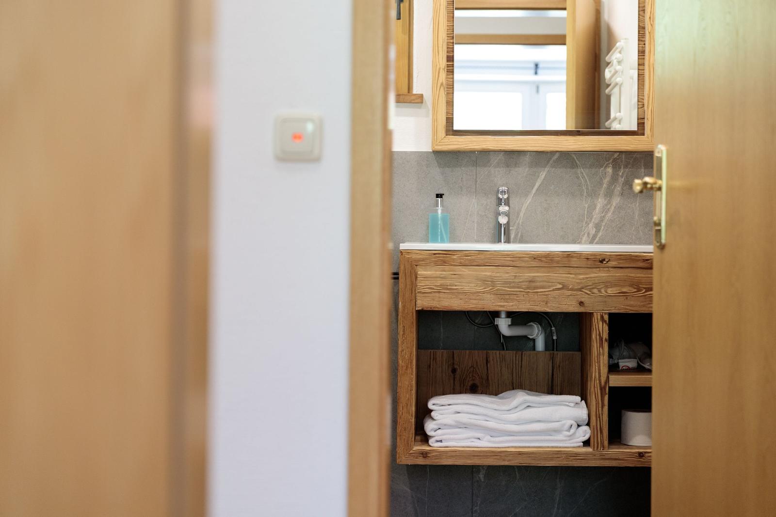 Bathroom with wooden sink, mirror, and folded towels.