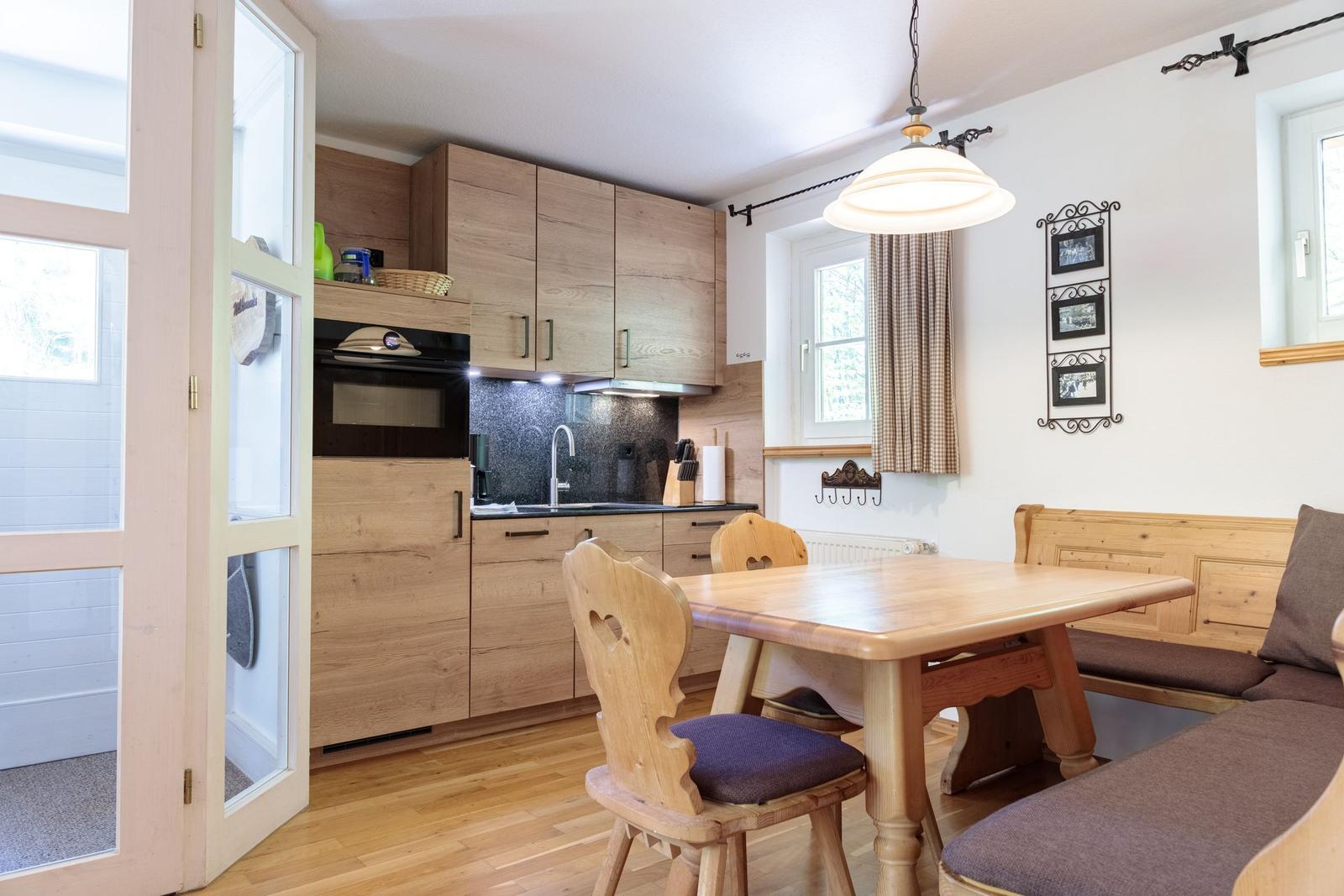 Kitchen with wooden furniture and dining area with table and benches.