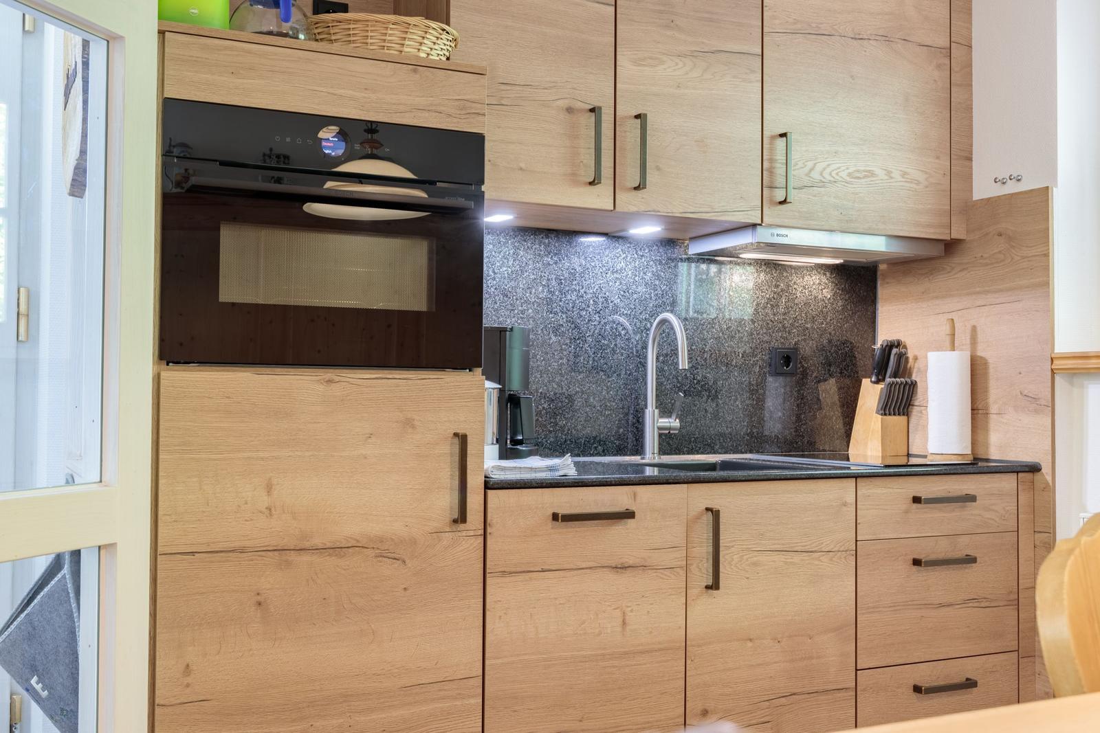 Kitchen with wooden cabinets, sink, and built-in oven.