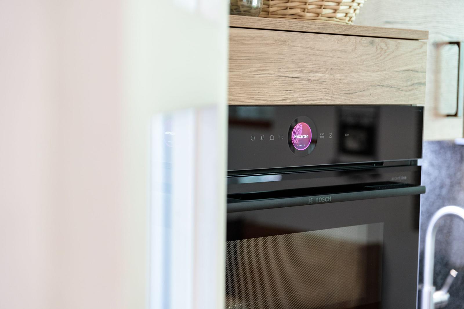 An integrated Bosch cooktop with touch display and wooden surface.