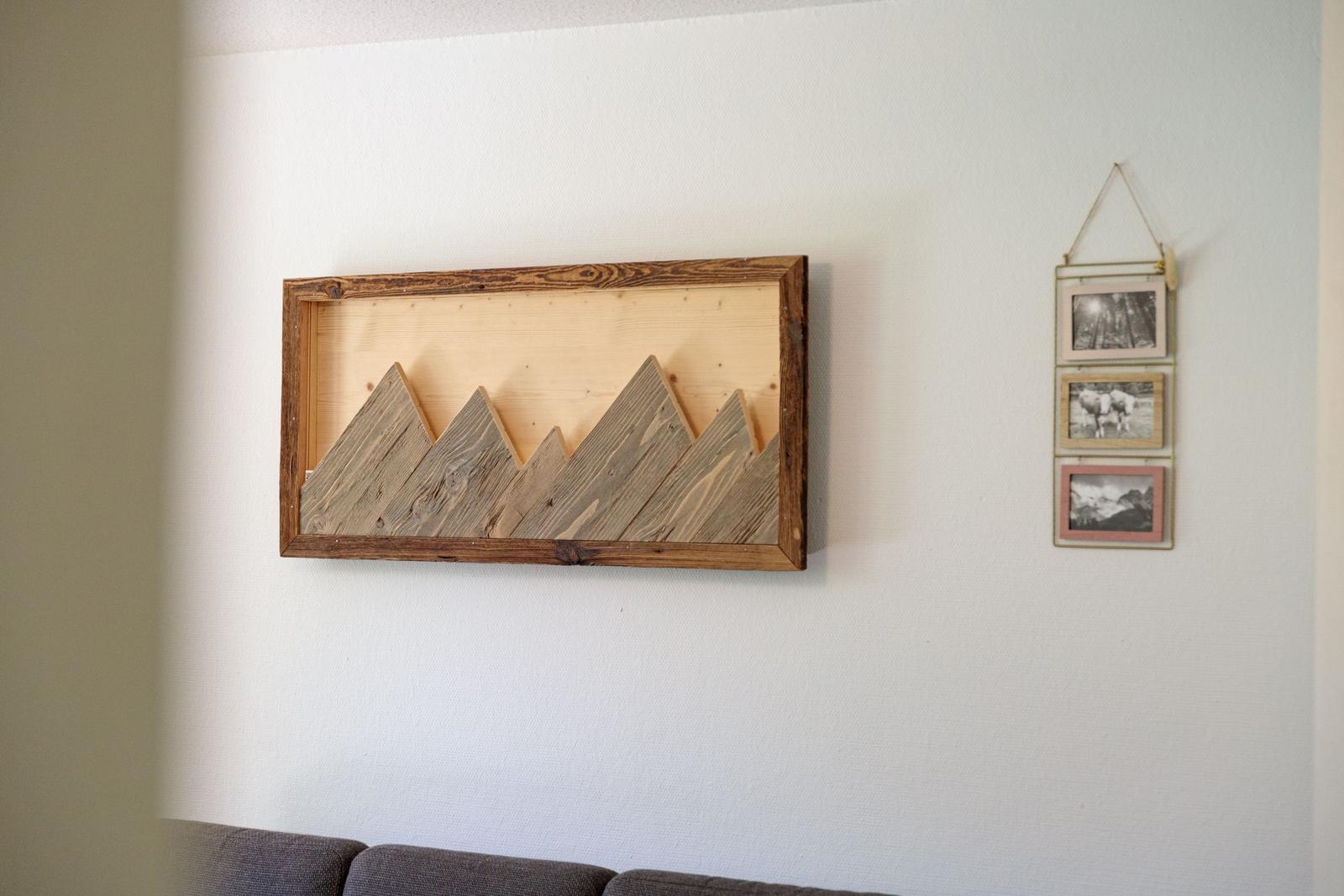 Wall with wood artwork and three photos