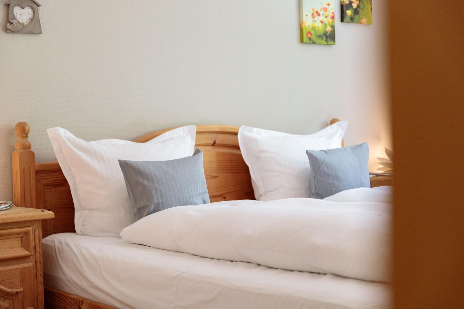 A bed with a wooden frame, white pillows, and a gray pillow.