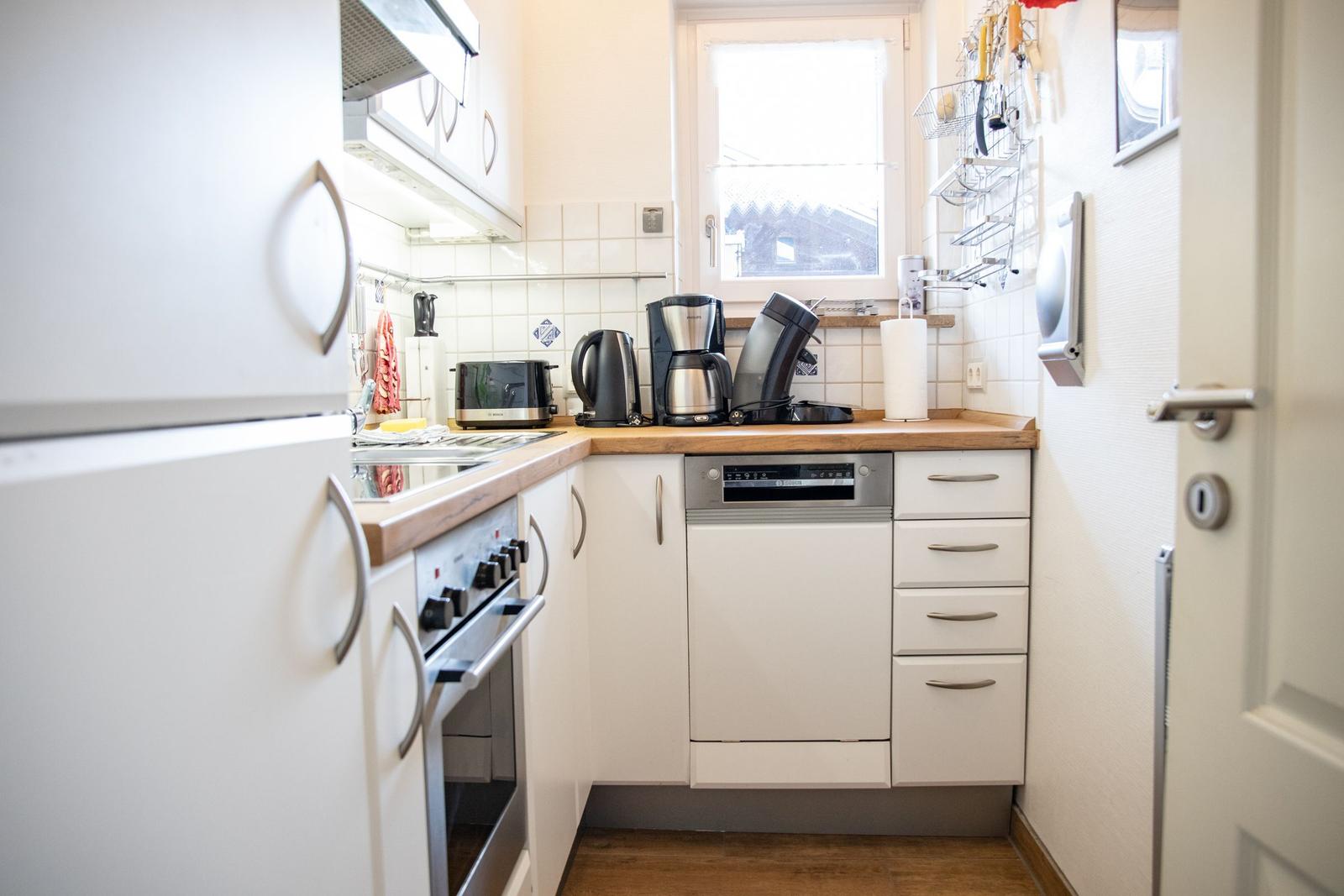 Kitchen with white cabinets, wooden countertop, and integrated dishwasher