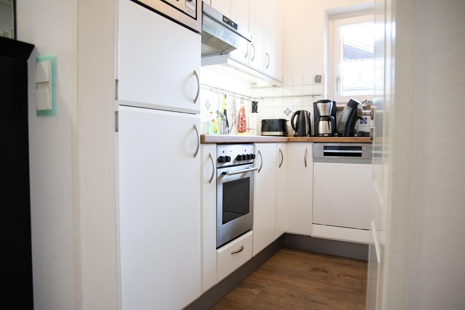Kitchen with white cabinets, stainless steel stove, and sink under window.