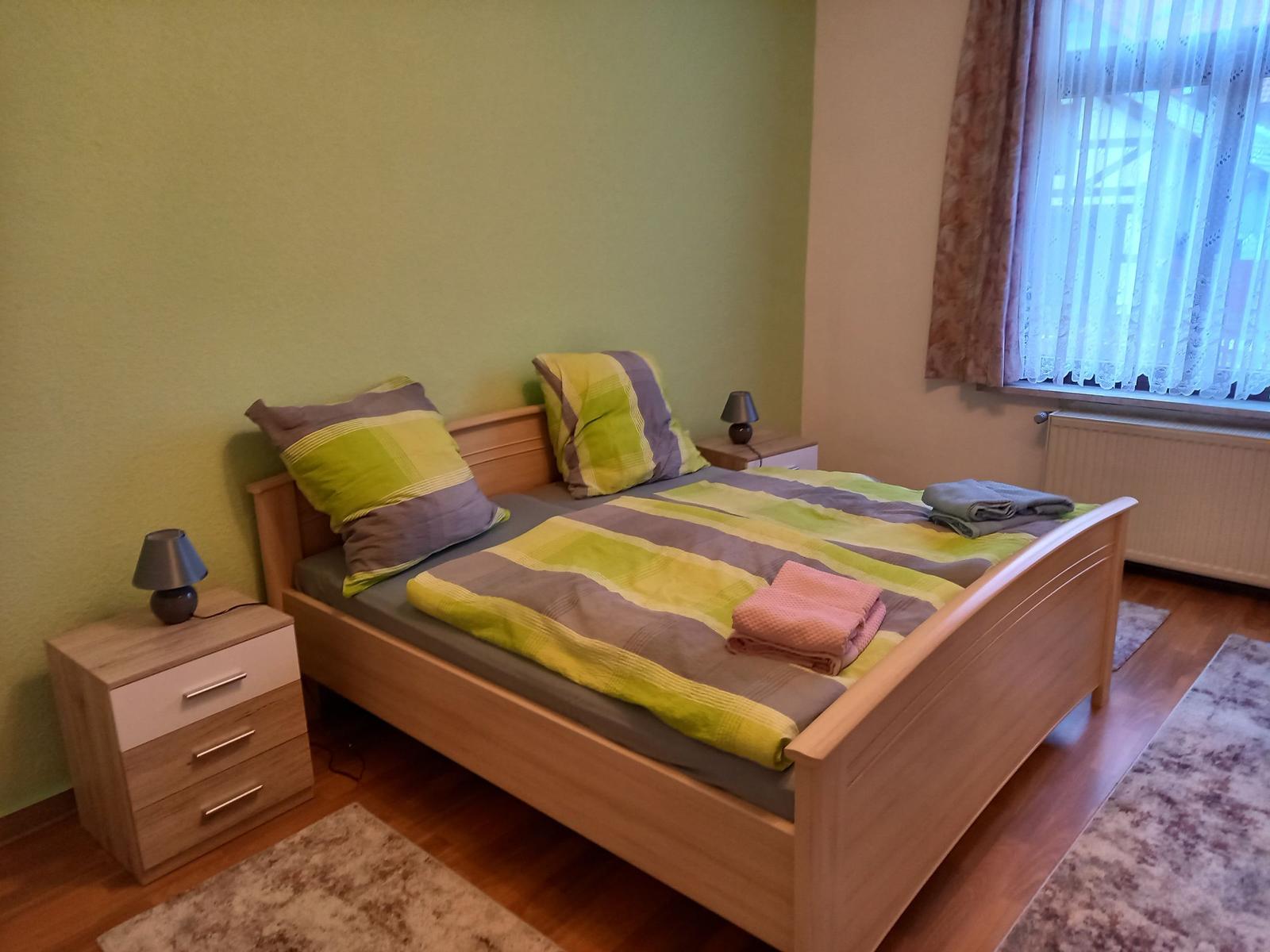 Ein Schlafzimmer mit Bett, Nachttisch und Fenster.