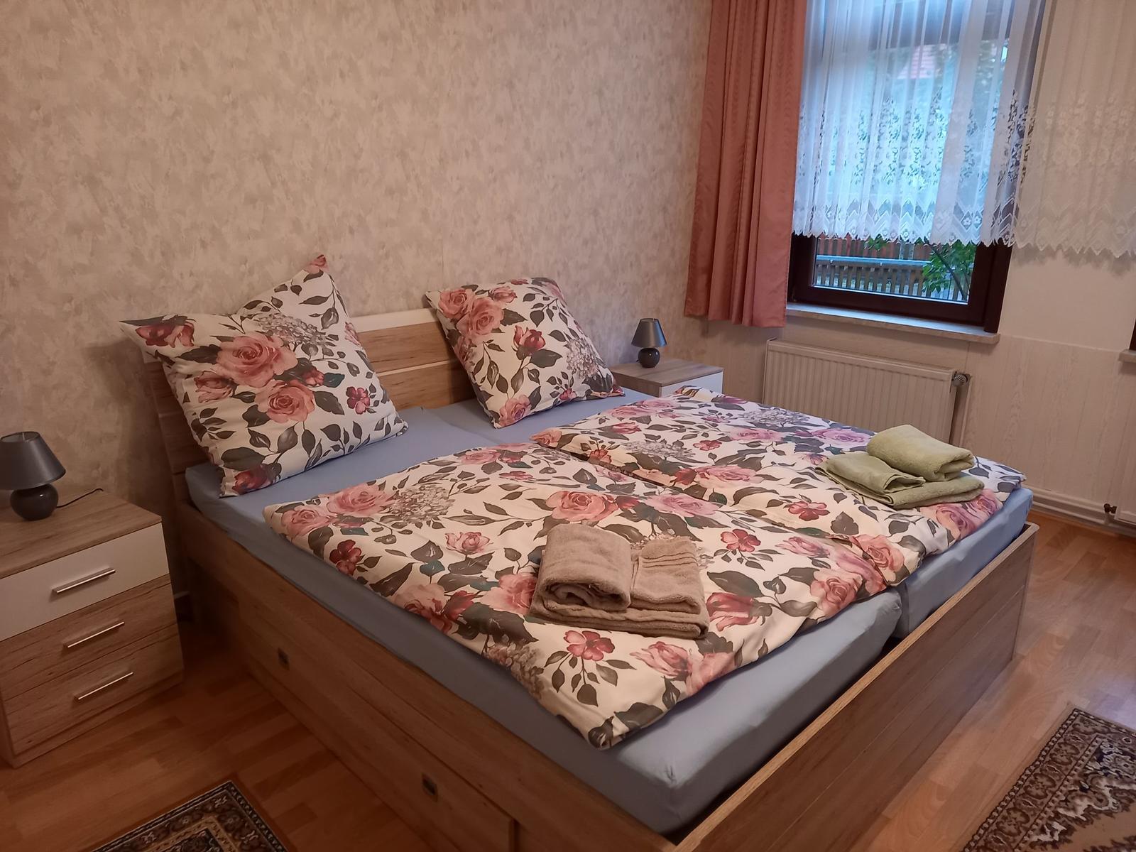 Schlafzimmer mit Doppelbett, floraler Bettwäsche und zwei Nachttischen.