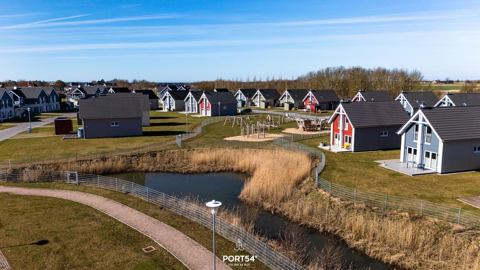 Modernes Ferienhaus mit Blick auf einen Teich und Spielplatz.