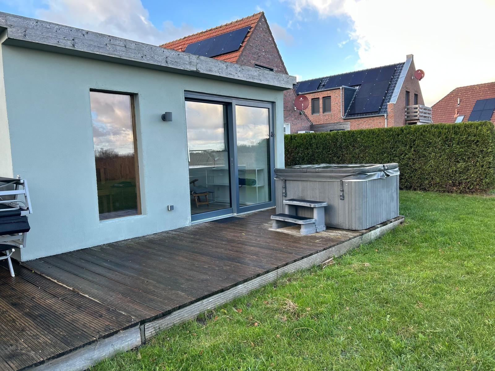 Moderne Terrasse mit Whirlpool und Holzdecke. Hintergrund: grüner Rasen und Hecke.