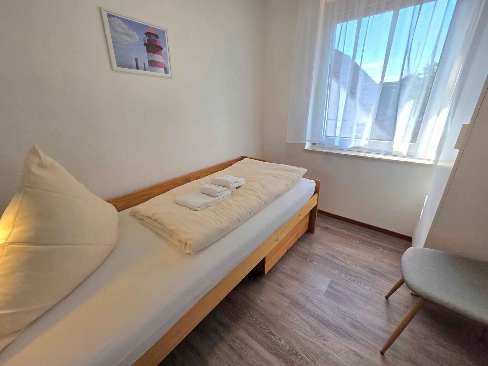 Ein Schlafzimmer mit einem Bett, einem Stuhl und einem Fenster mit Vorhängen.