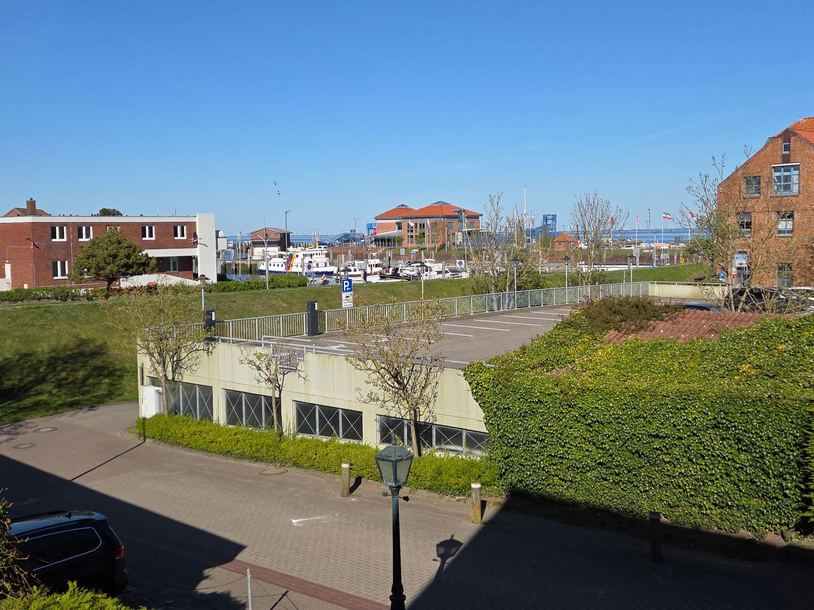 Parkplatz mit Blick auf Hafen und Gebäude unter blauem Himmel.