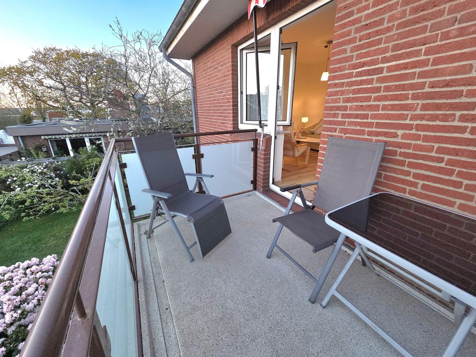 Terrasse mit zwei Liegestühlen und Tisch, Blick ins Haus und Garten.