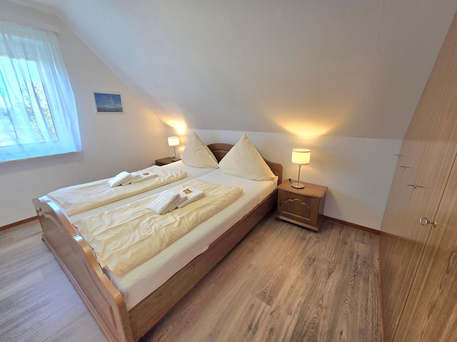 Ein Schlafzimmer mit Doppelbett, zwei Nachttischen und einem Kleiderschrank.