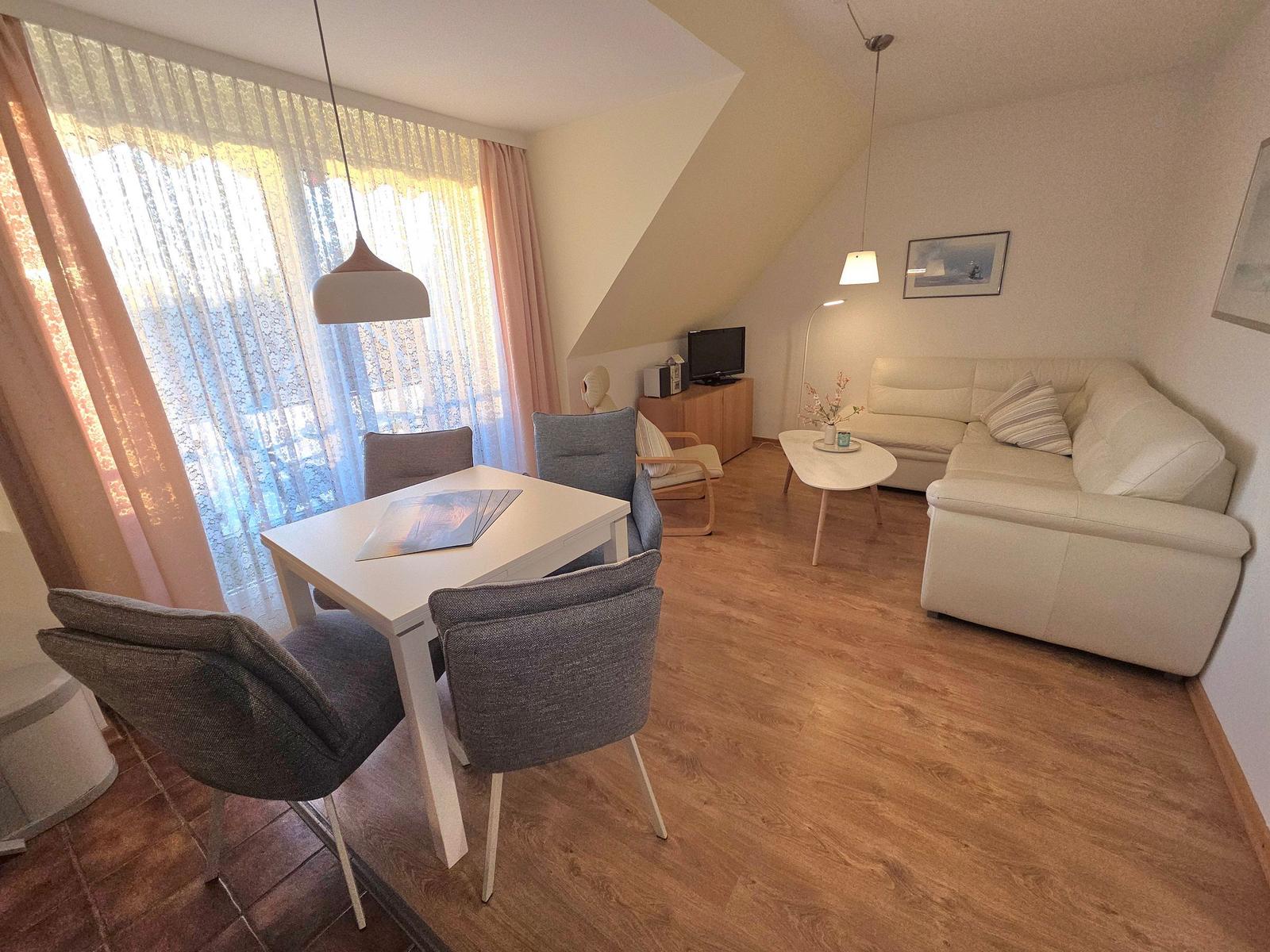 Wohn- und Essbereich mit Sofa, Tisch und Stühlen unter schrägen Decken.